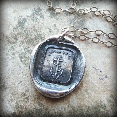 Anchor wax seal necklace on a marble backdrop.