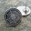 Compass wax seal earrings on marble counter