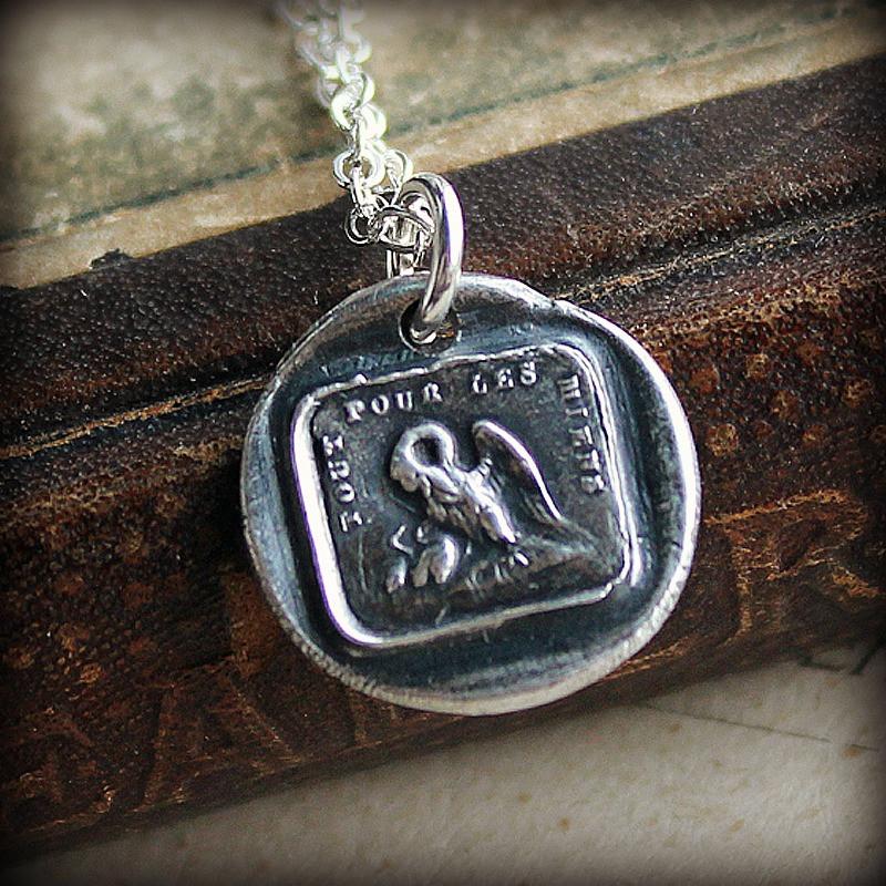 A Mother's Love Wax Seal Necklace on a stack of antique books.