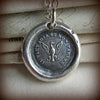 An eagle wax seal medallion on a chain.