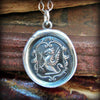 A silver griffin wax seal crest laying over a stack of old style book covers.