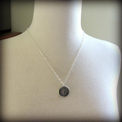 Compass wax seal necklace around a mannequin.